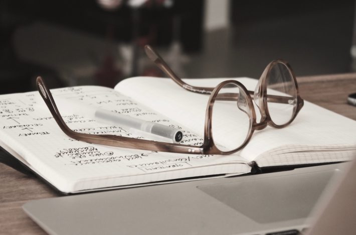 briller med grå stel på toppen af ​​notesbogen